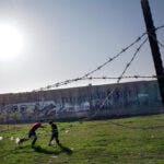 Två barn spelar fotboll framför muren i Palestina