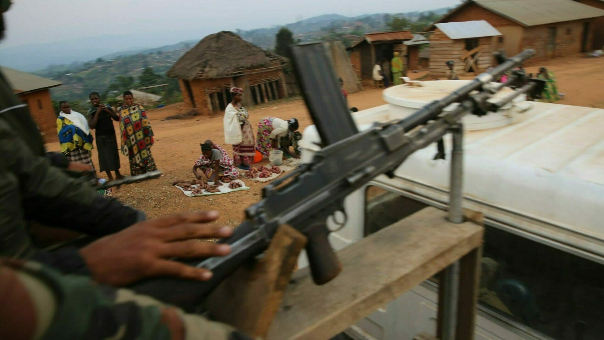 Soldiers with a weapon passing a group of people along the way.