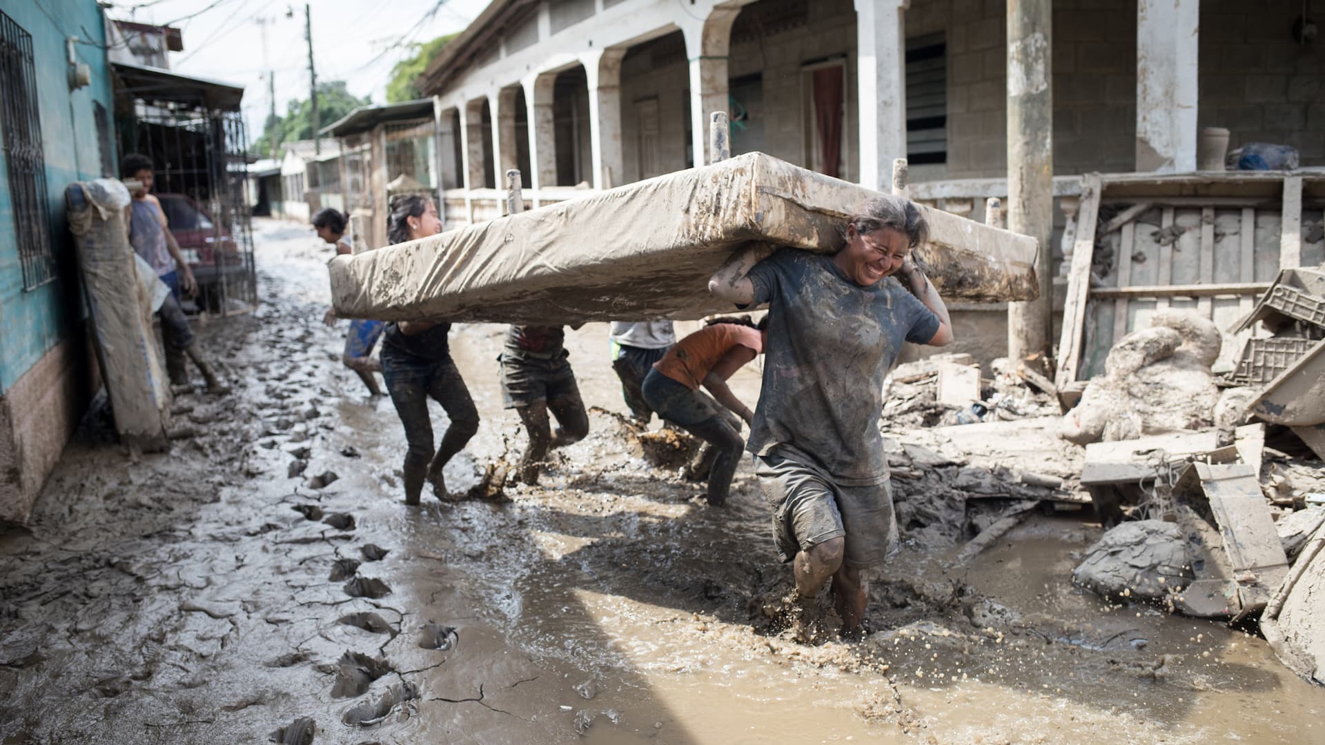 Människor bär en säng på en översvämmad gata