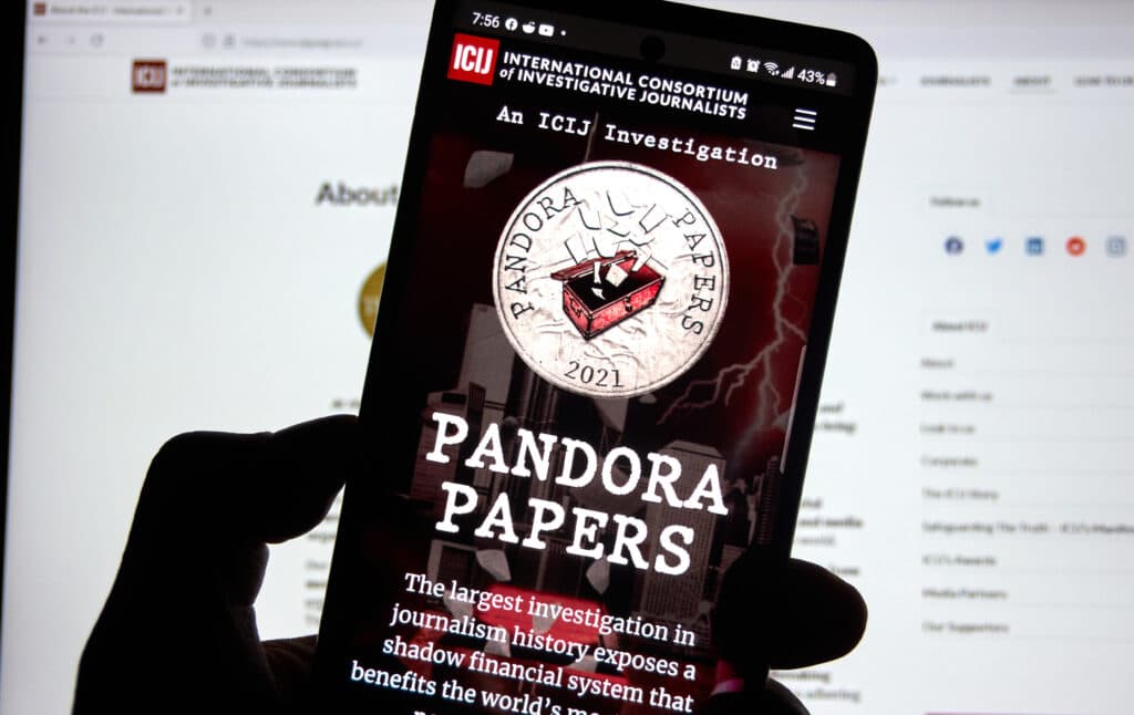 Mobiltelefon framför skärm med avslöjandet om pandora papers.