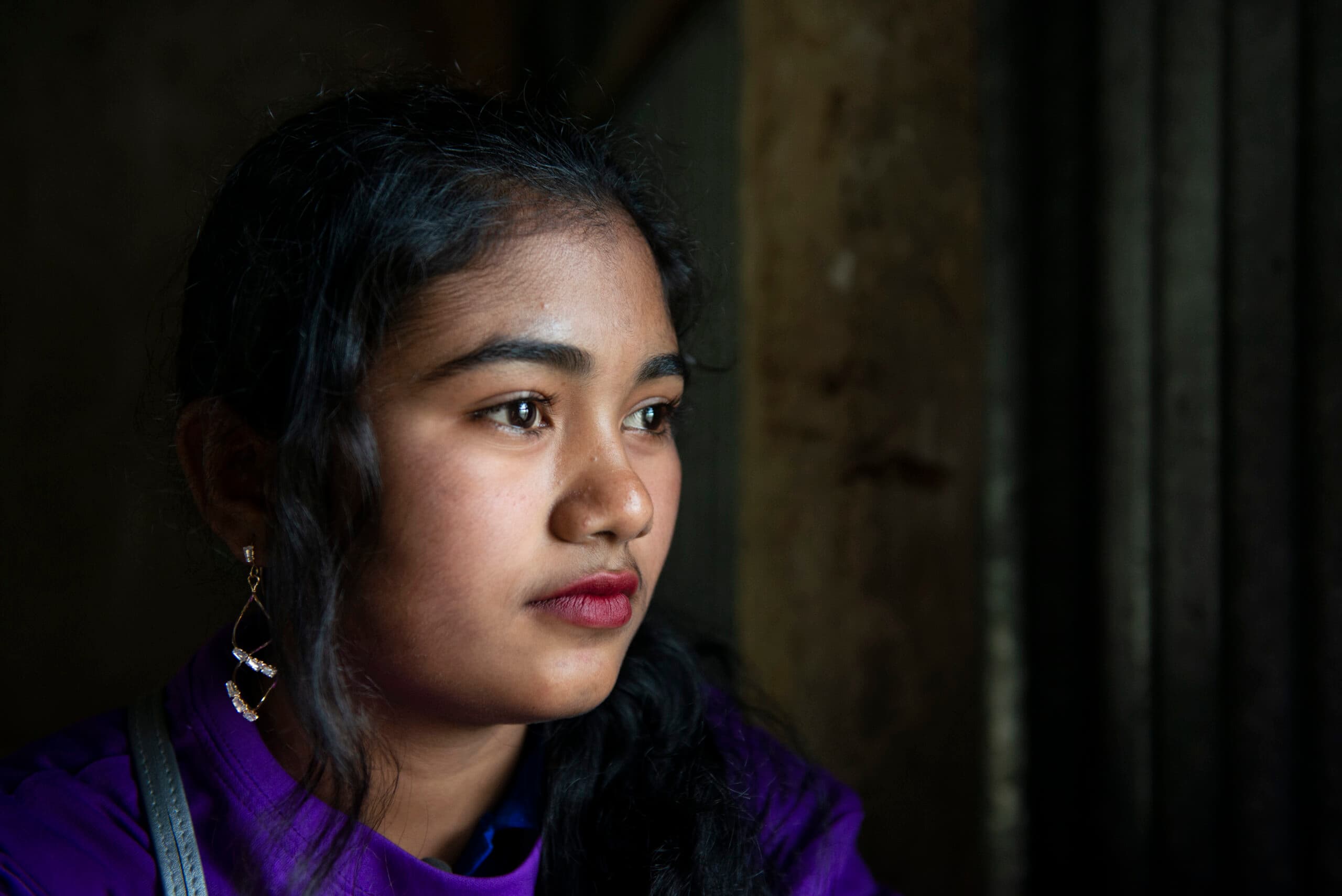 En närbild av en flicka med mörk bakgrund.