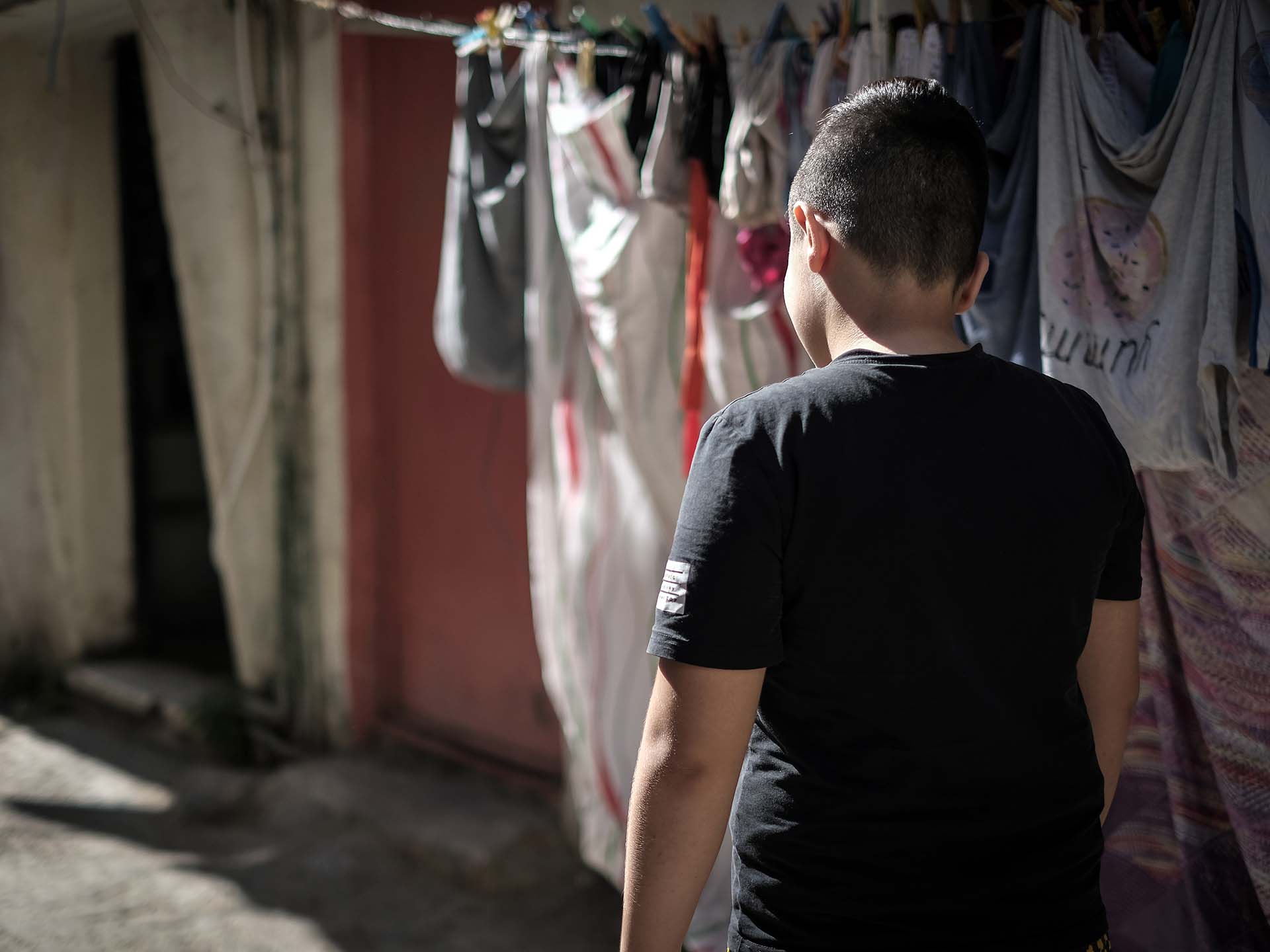 Ryggen på en pojke framför ett klädstreck.