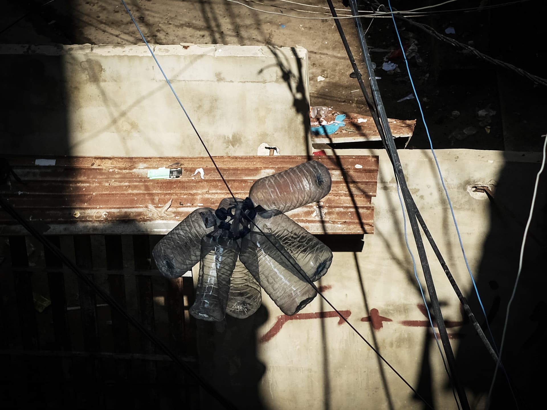 En betongvägg med delar av plåt och elledningar som hänger framför.