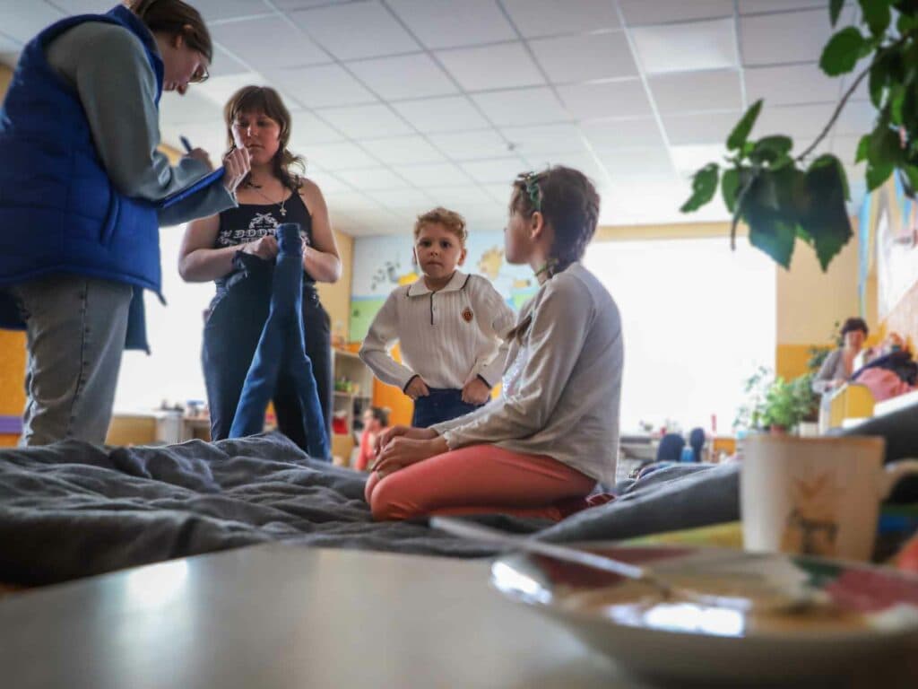 En man i väst pratar med en kvinna och två barn