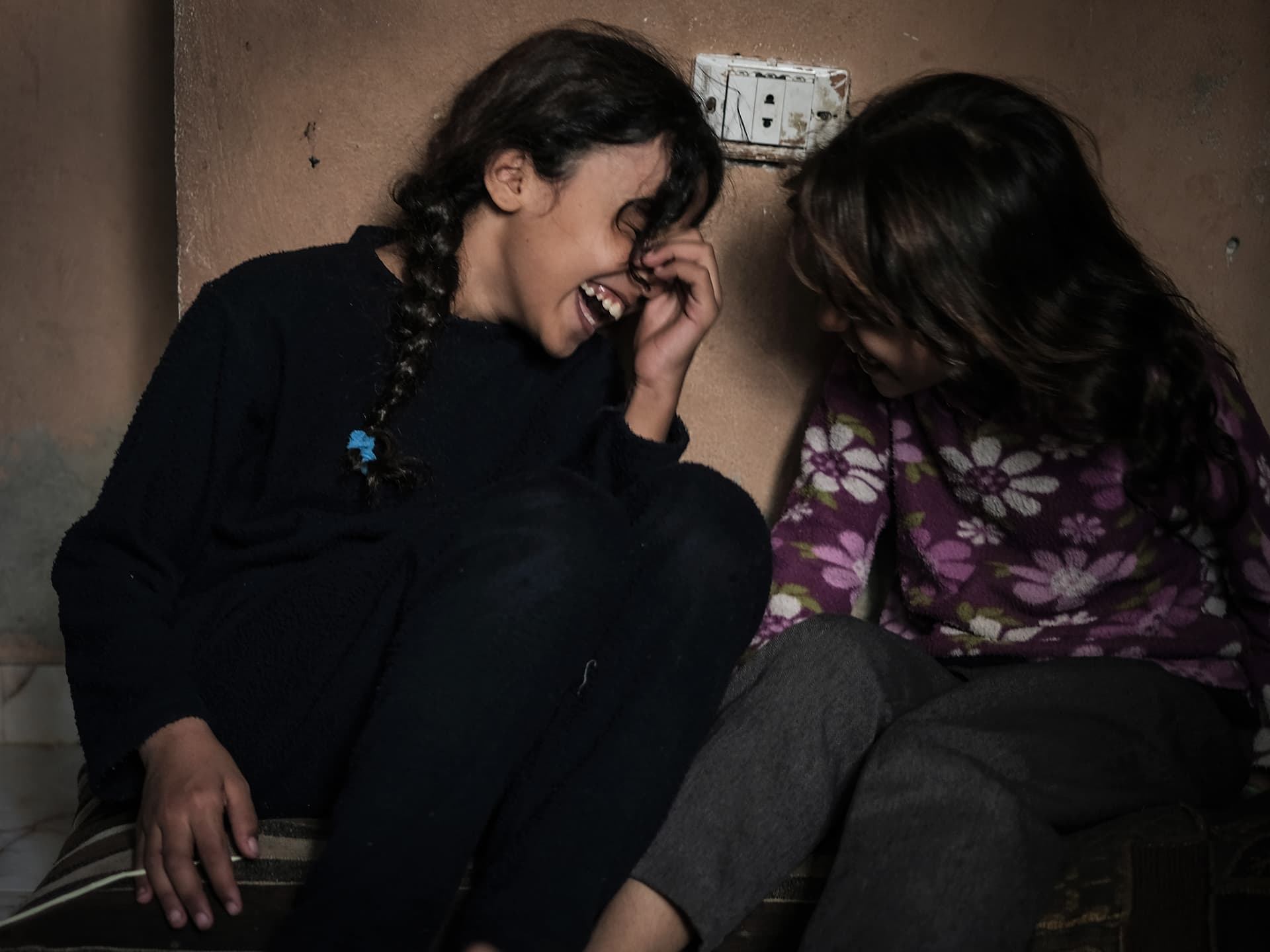 Två flickor sitter och skrattar med huvudena vända mot varandra.