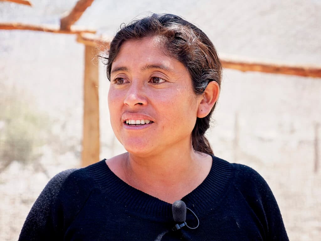 En närbild av en kvinna med mörkt hår som står utomhus.,