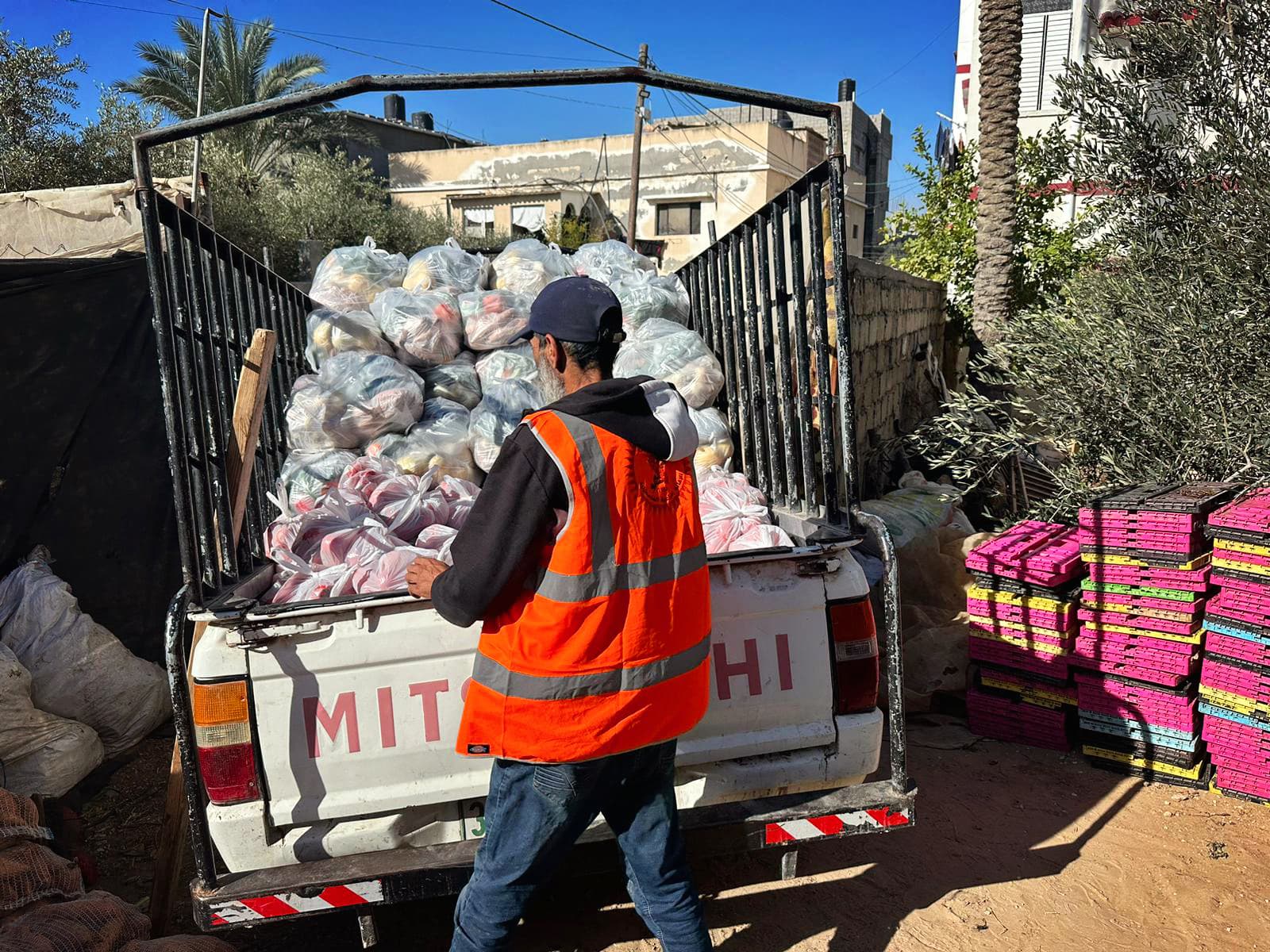 En lastbil med en massa kassar på flaket och en man i reflexväst som lyfter ur kassar.