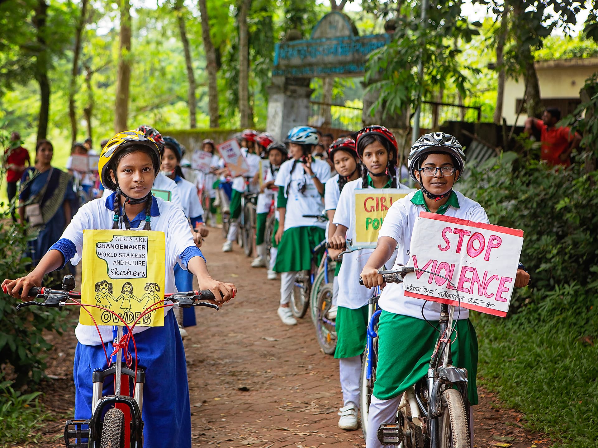 Flera tjejer i skoluniformer och cykelhjälmar står på rad med en varsin cykel.
