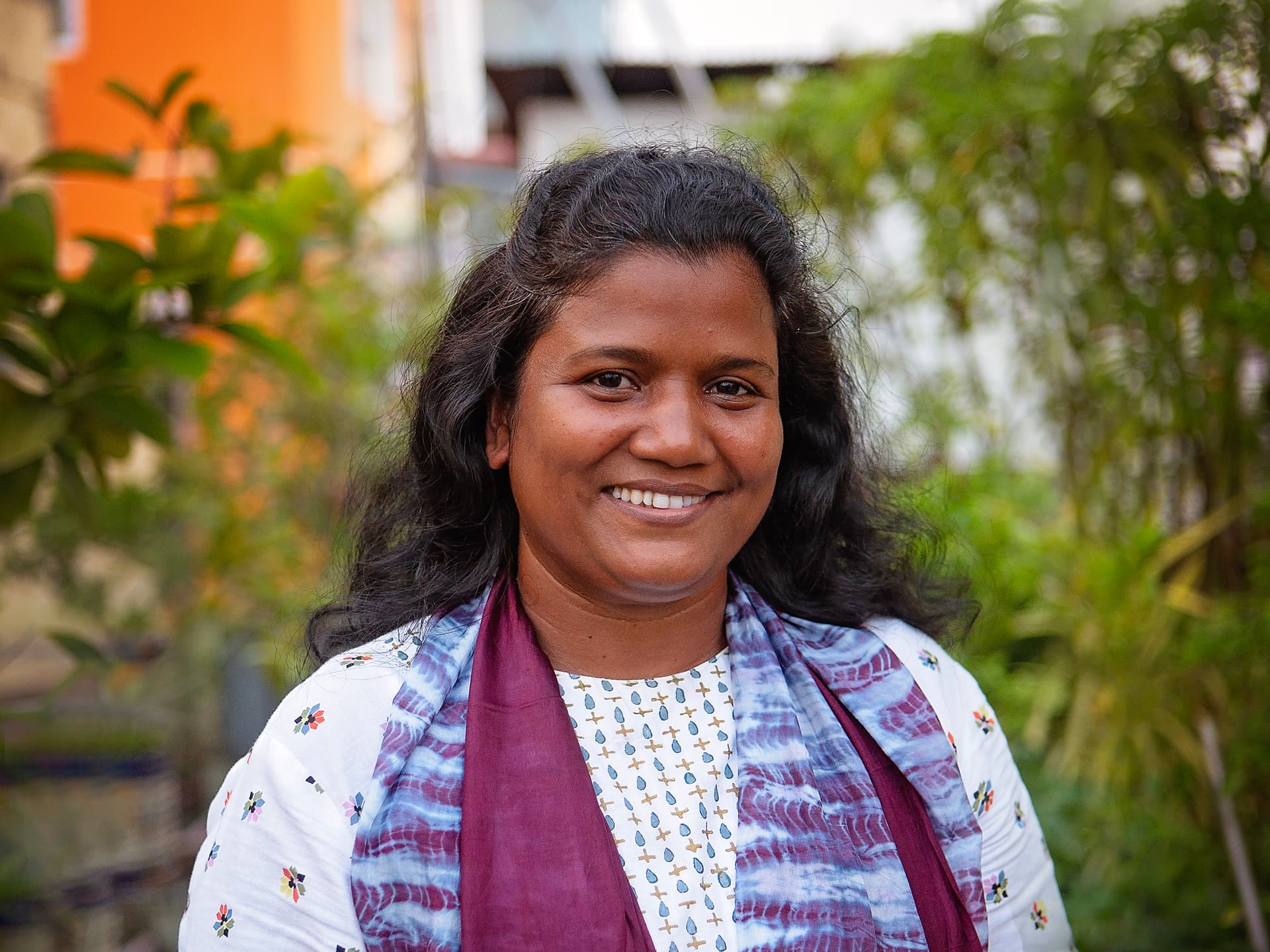 Ett porträtt av en kvinna med mörkt hår, ljus blus och violett sjal.