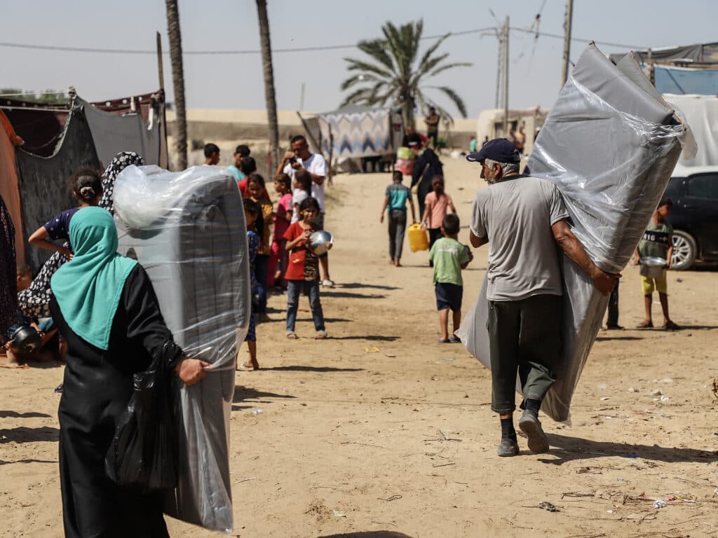 En miljö i Palestina där människor bär på madrasser.