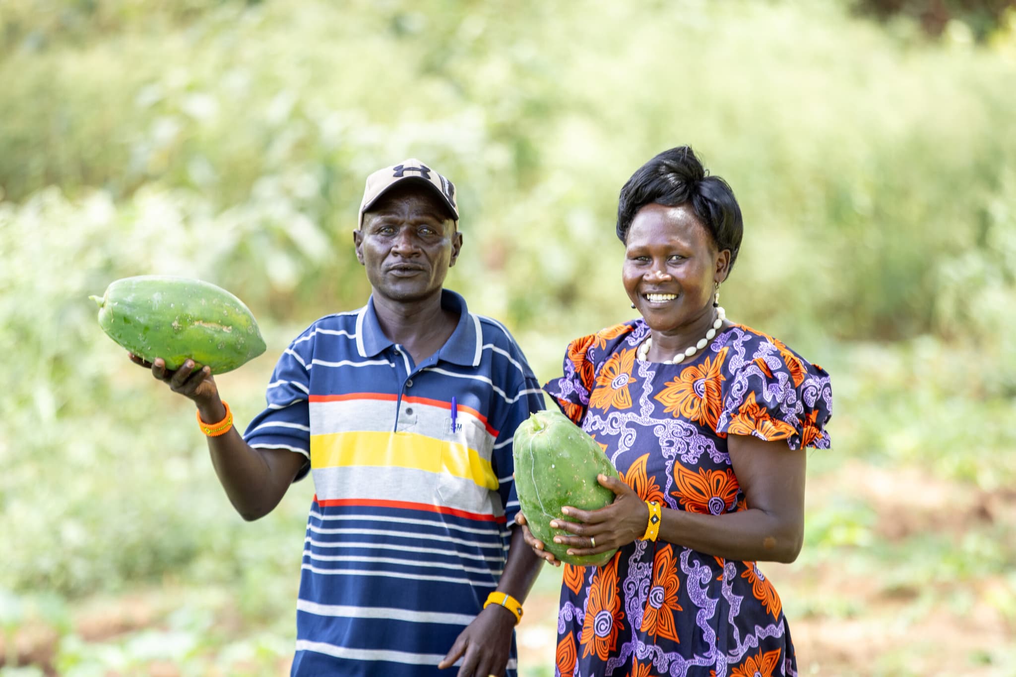 Två jordbrukare visar upp skördad frukt.
