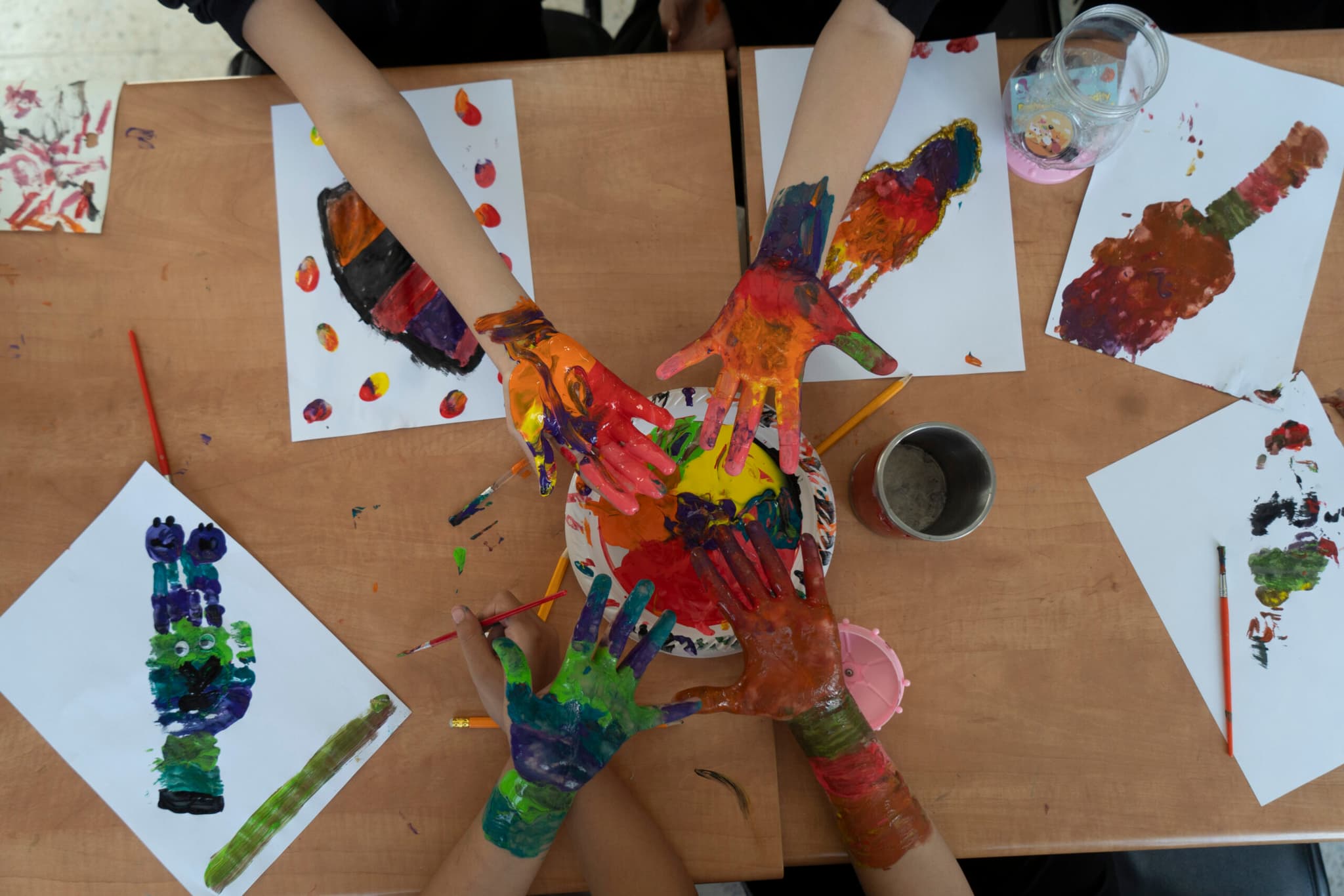 Barnhänder som är målade i olika färger hålls upp framför kameran.