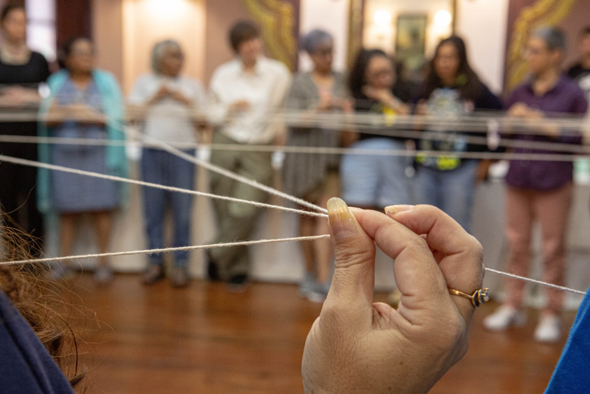 En grupp med människor gör en gruppövning och håller i flera snören som liknar ett spindelnät.