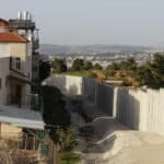 A high concrete wall next to an appartement building.