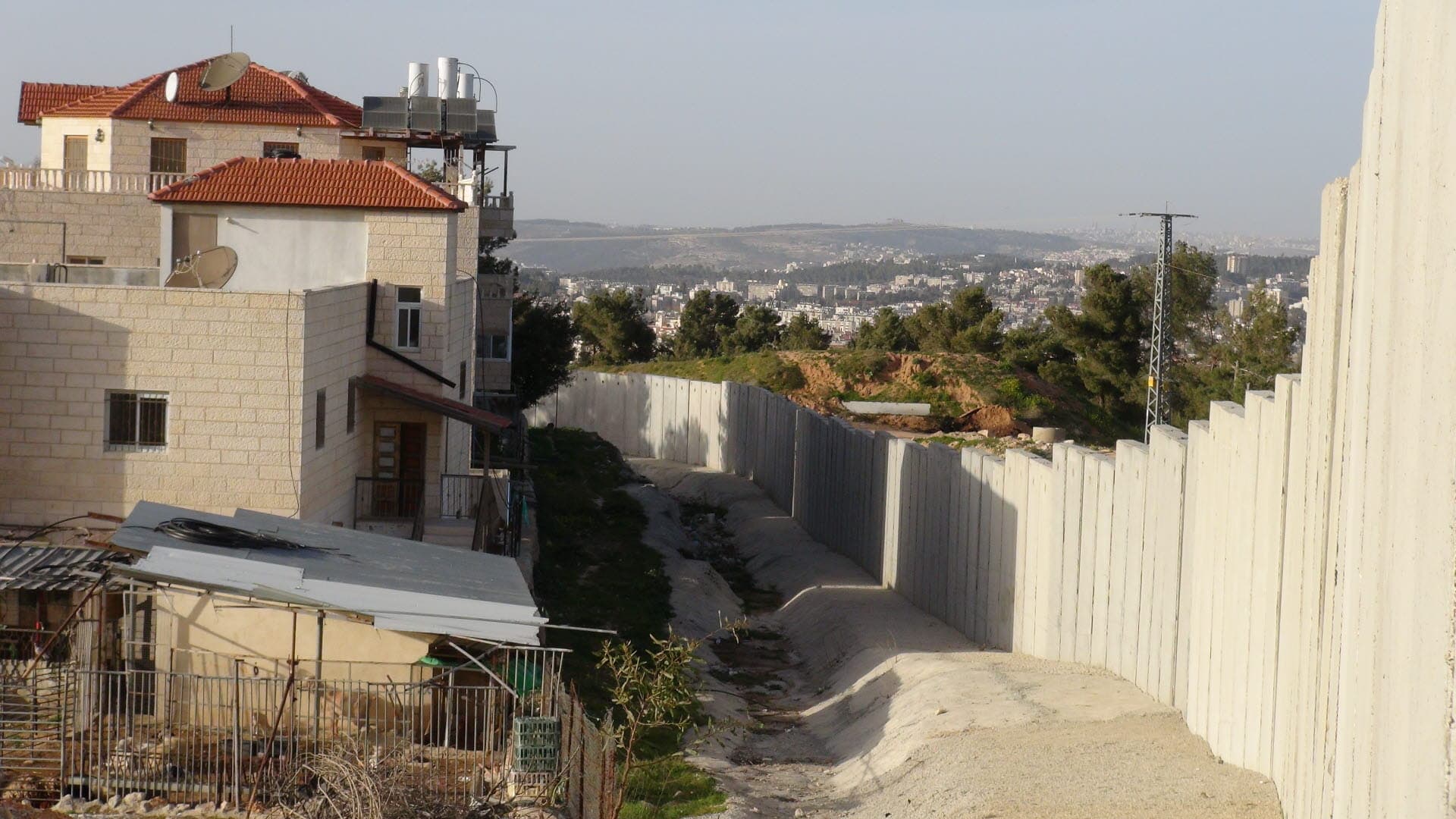 A high concrete wall next to an appartement building.