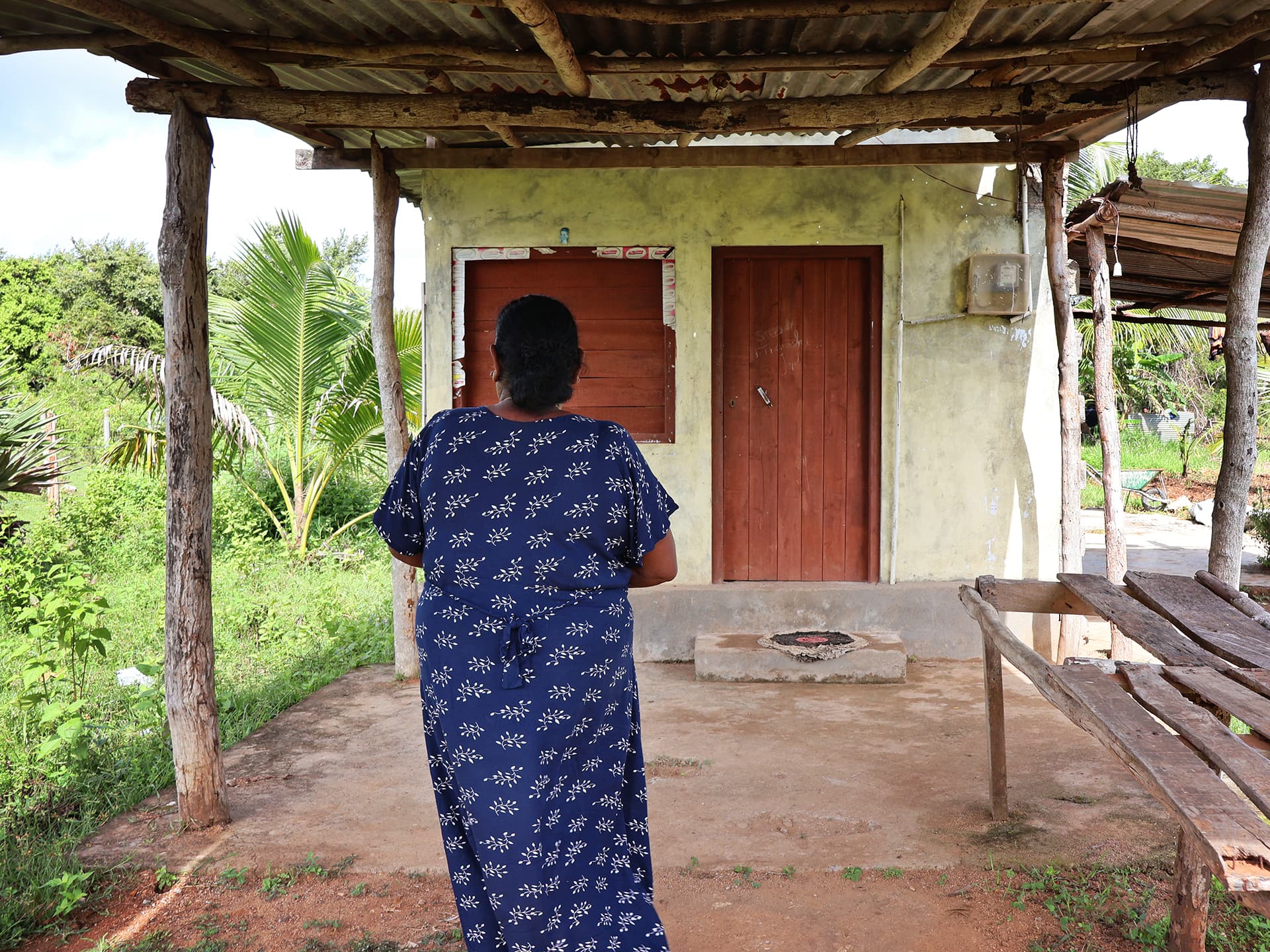 The back of a woman wearing a blue dress walking towards a house.