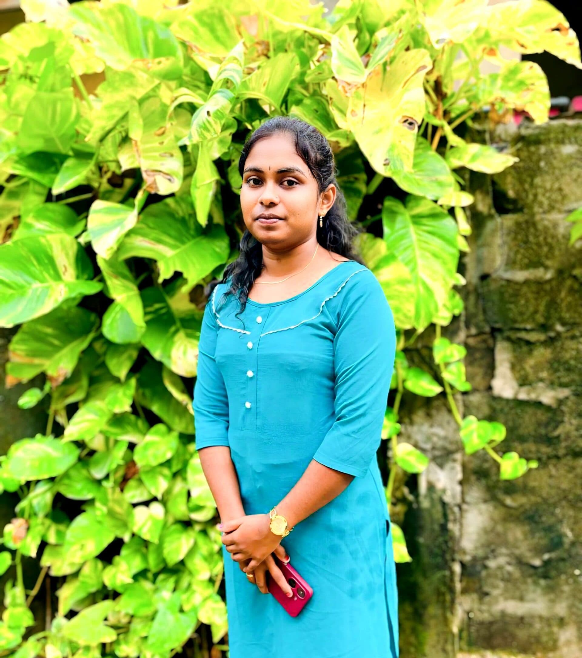 A girl in a blue dress standing in front of a tree.