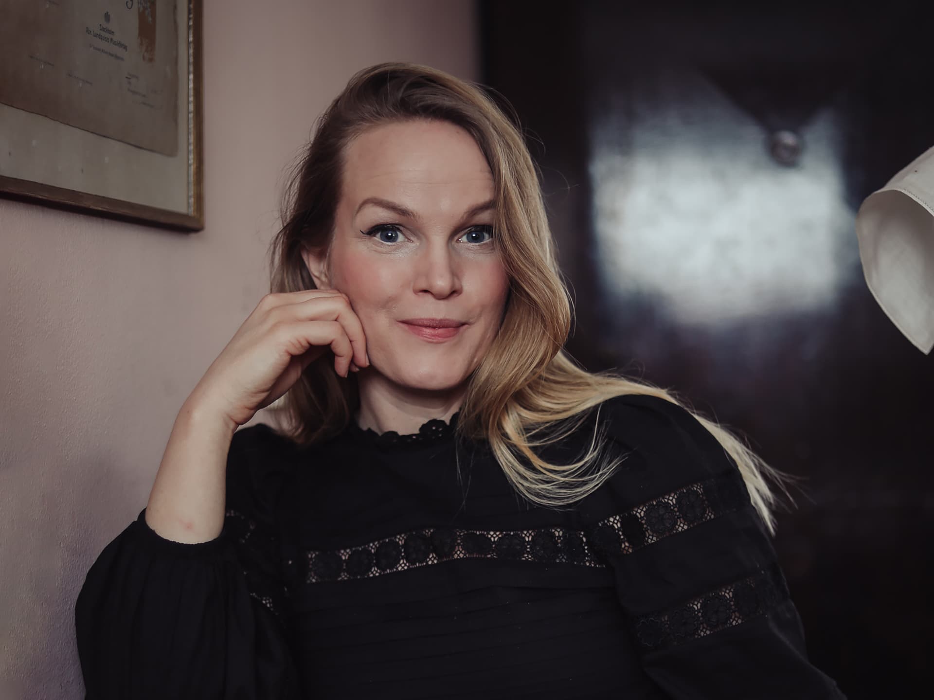Ett porträtt av Emma Sundh som sitter i mörka kläder med handen mot hakan.