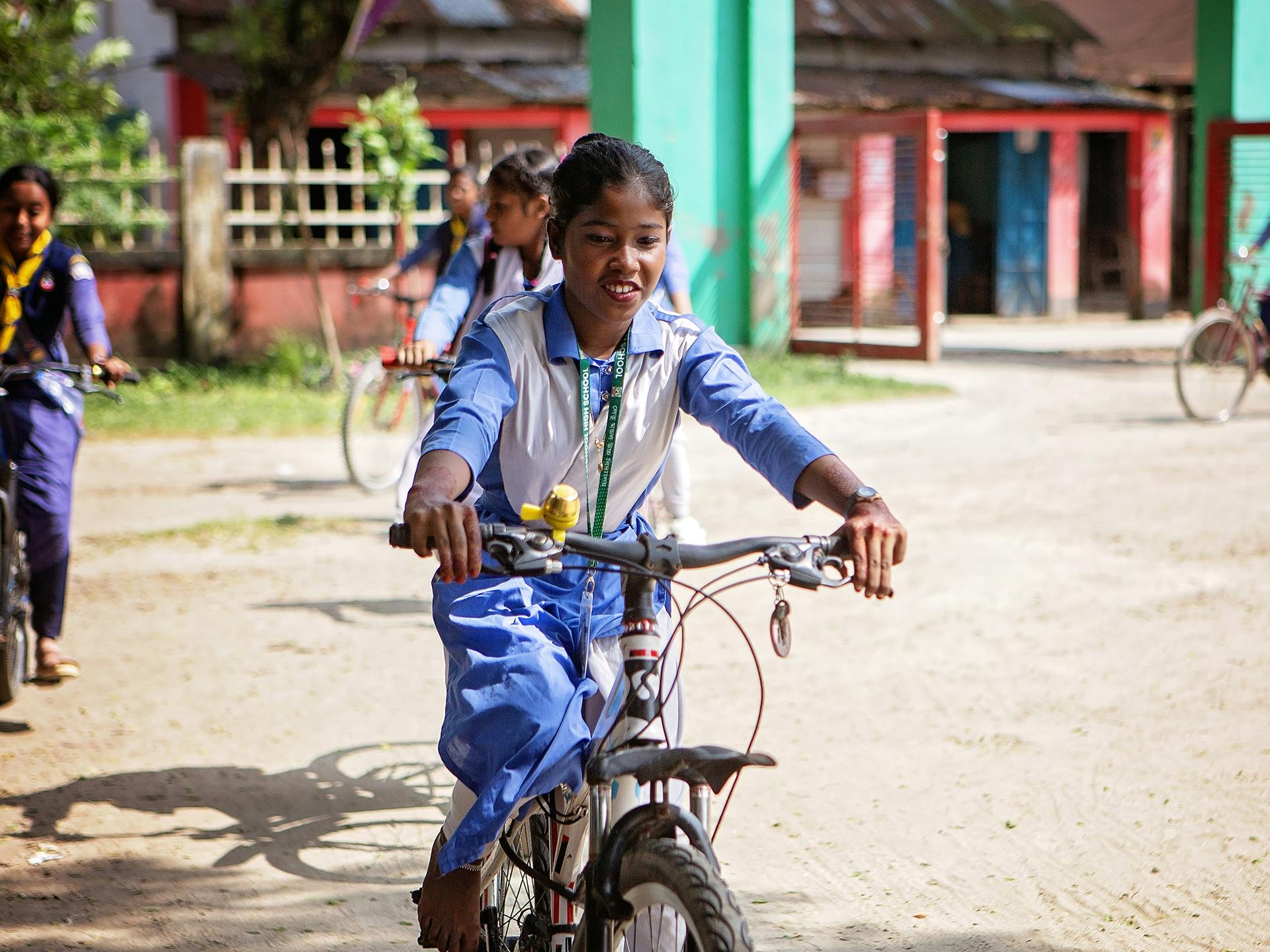 En flicka i skoluniform cyklar på en skolgård.