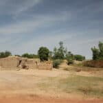 A hut of bricks and in the background trees.