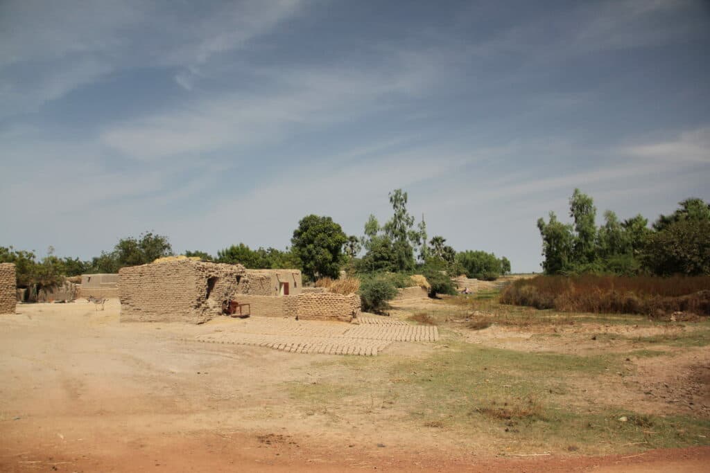 A hut of bricks and in the background trees.