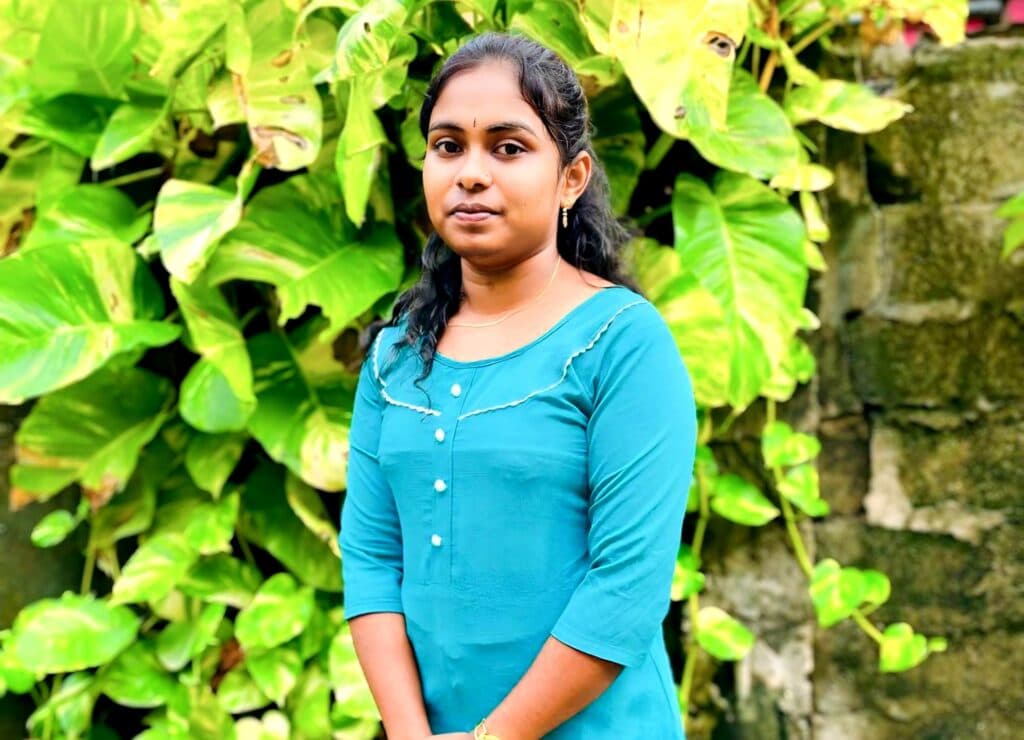 A girl in a blue dress standing in front of a tree.