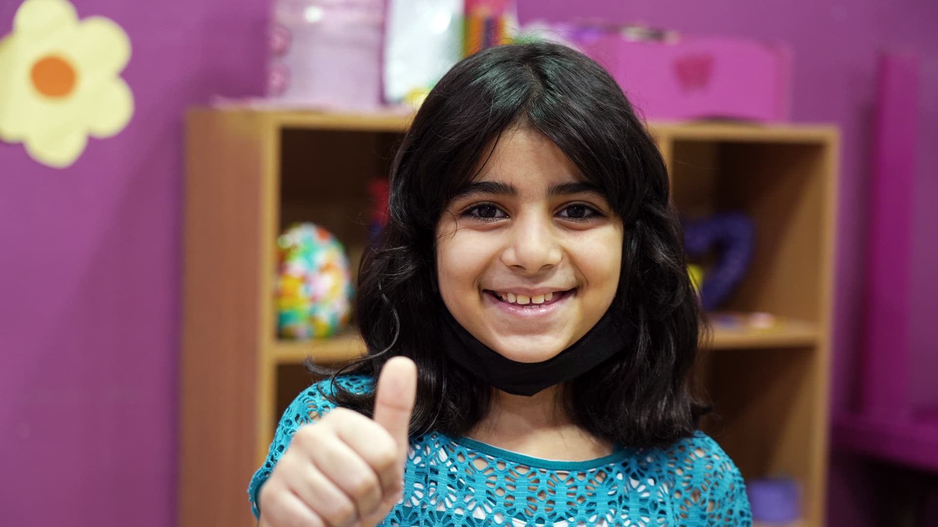 Foto: Adib Farhat En flicka framför en bokhylla gör tummen upp