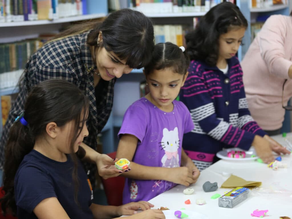 Foto: Abu Rahmah Barn vid ett bord som pysslar med lera