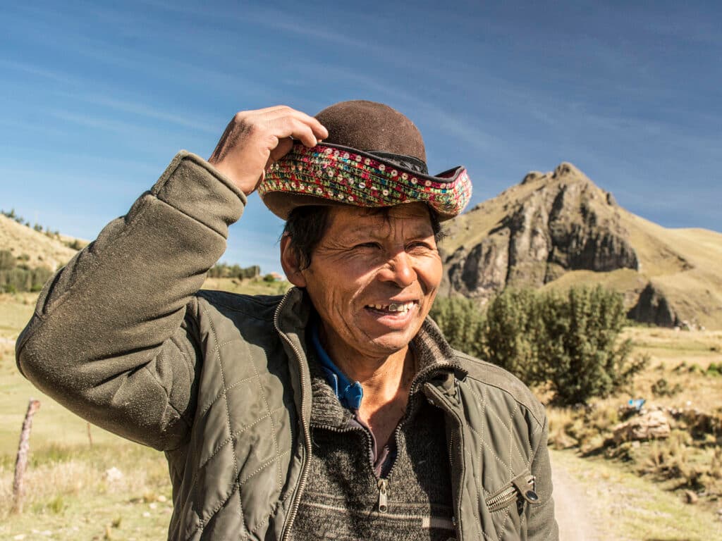 Porträtt av en äldre man med en hatt. I bakgrunden syns berg och slätter.