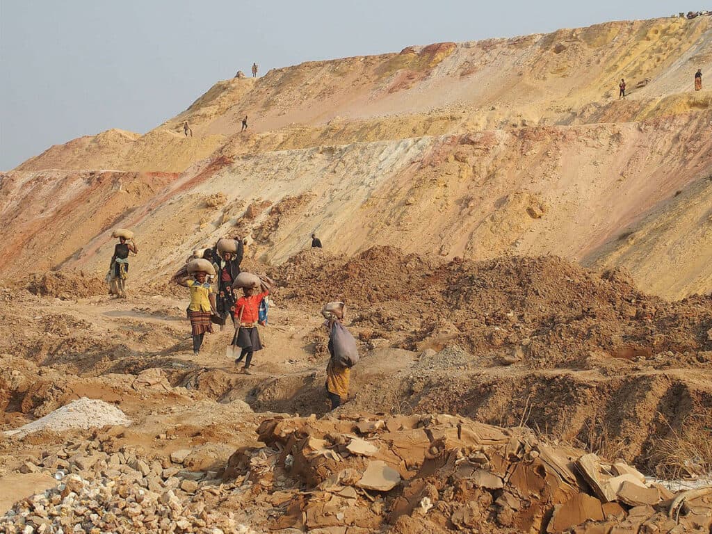 Människor bär på bylten i ökenområde