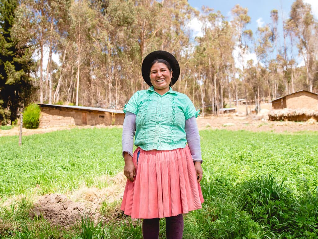 Foto: Siara Horna En kvinna med hatt och turkos blus står på en gräsmatta.