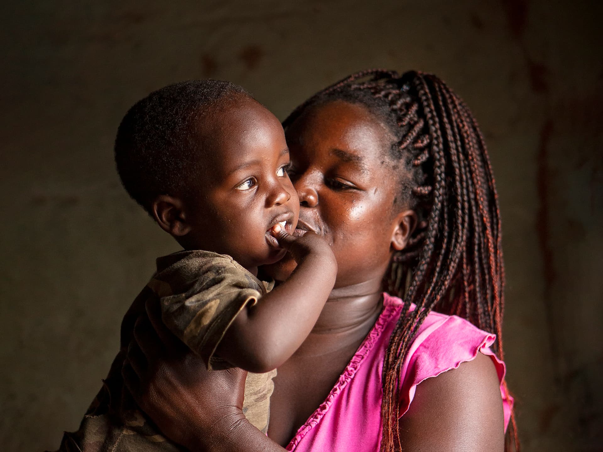 Foto: Diakonia En kvinna i rosa blus håller om och pussar ett litet barn i brun tröja.