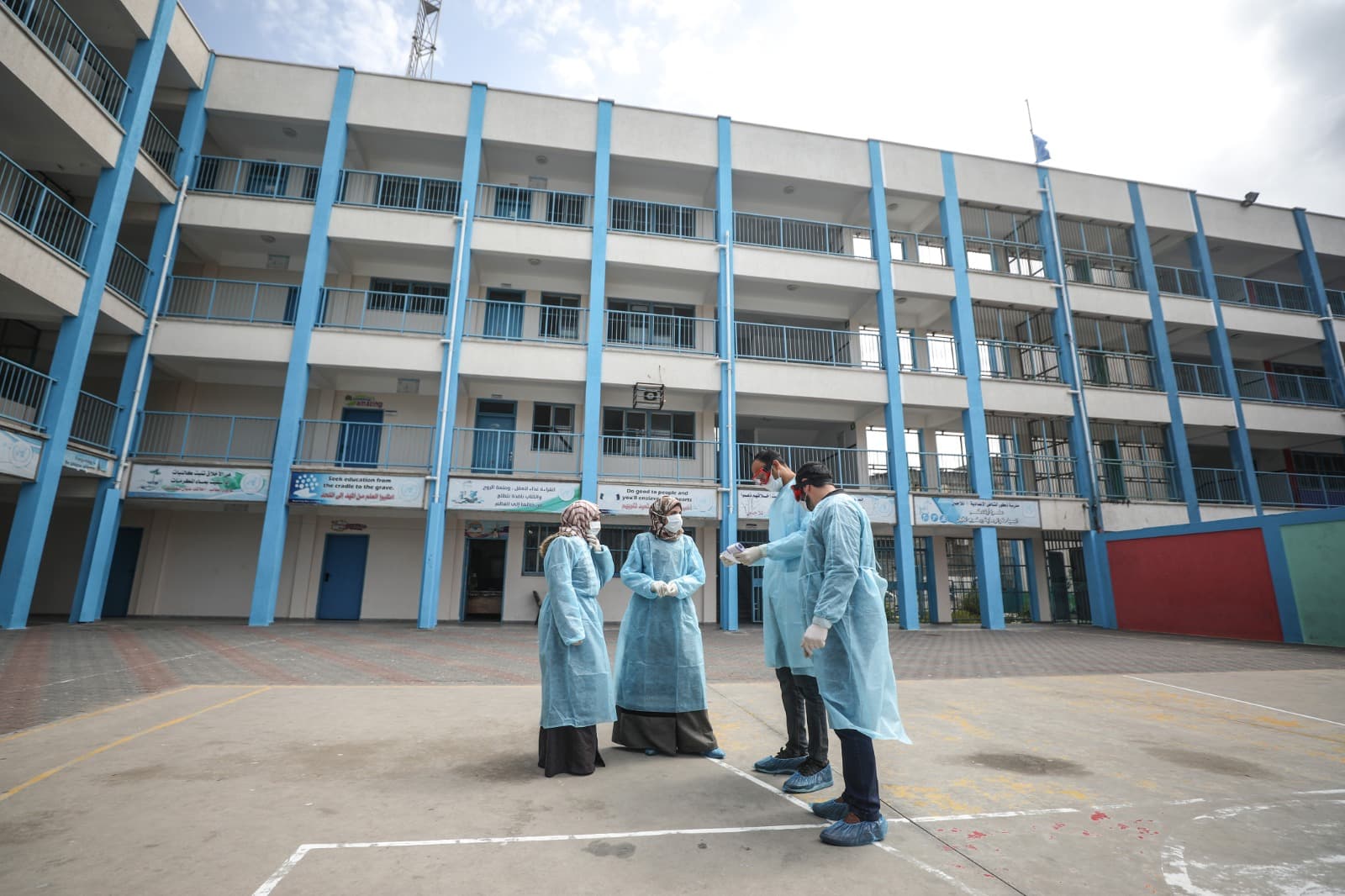 Health workers in protective gear discussing with each other, and in the background a tall building. Health workers in protective gear discussing with each other, and in the background a tall building.