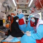 Medial personnel examine a woman in an ambulance car.