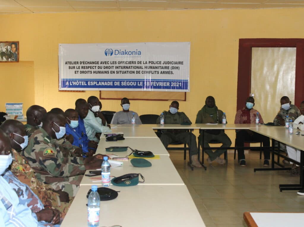 A group in military uniform sitting around a table listening to a presentation. A group in military uniform sitting around a table listening to a presentation.