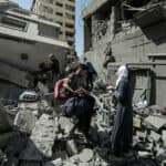 People climbing over the rubble of a destroyed building.