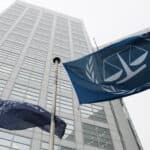 Blue flags of the International Criminal Court in front of the Court's office tower.