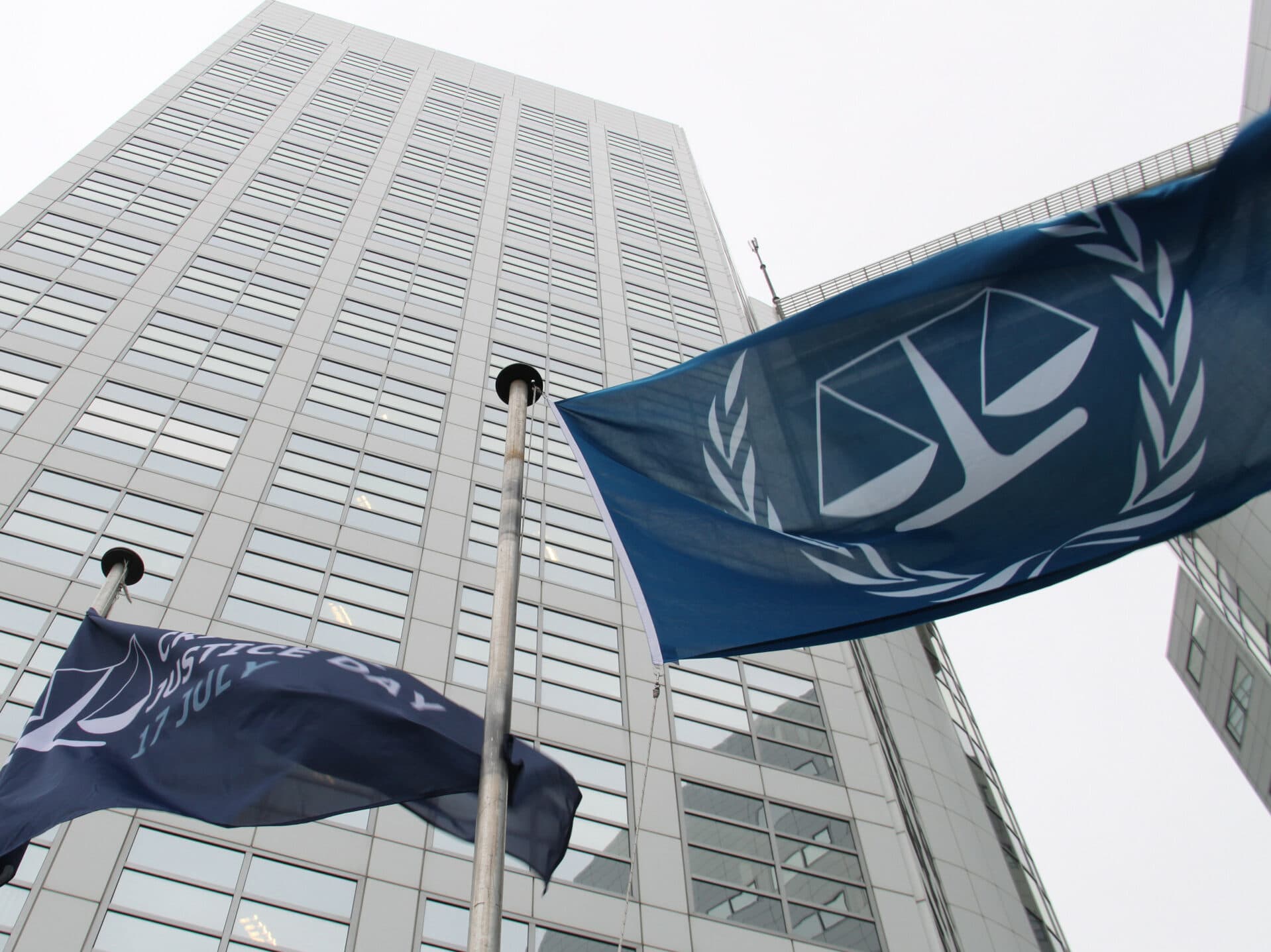 Blue flags of the International Criminal Court in front of the Court's office tower. Blue flags of the International Criminal Court in front of the Court's office tower.