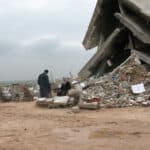 A man and a woman in front of destroyed building.
