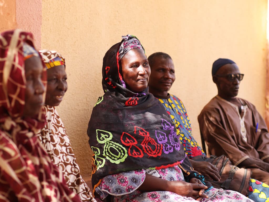 A woman sitting by a wall with a group of people.