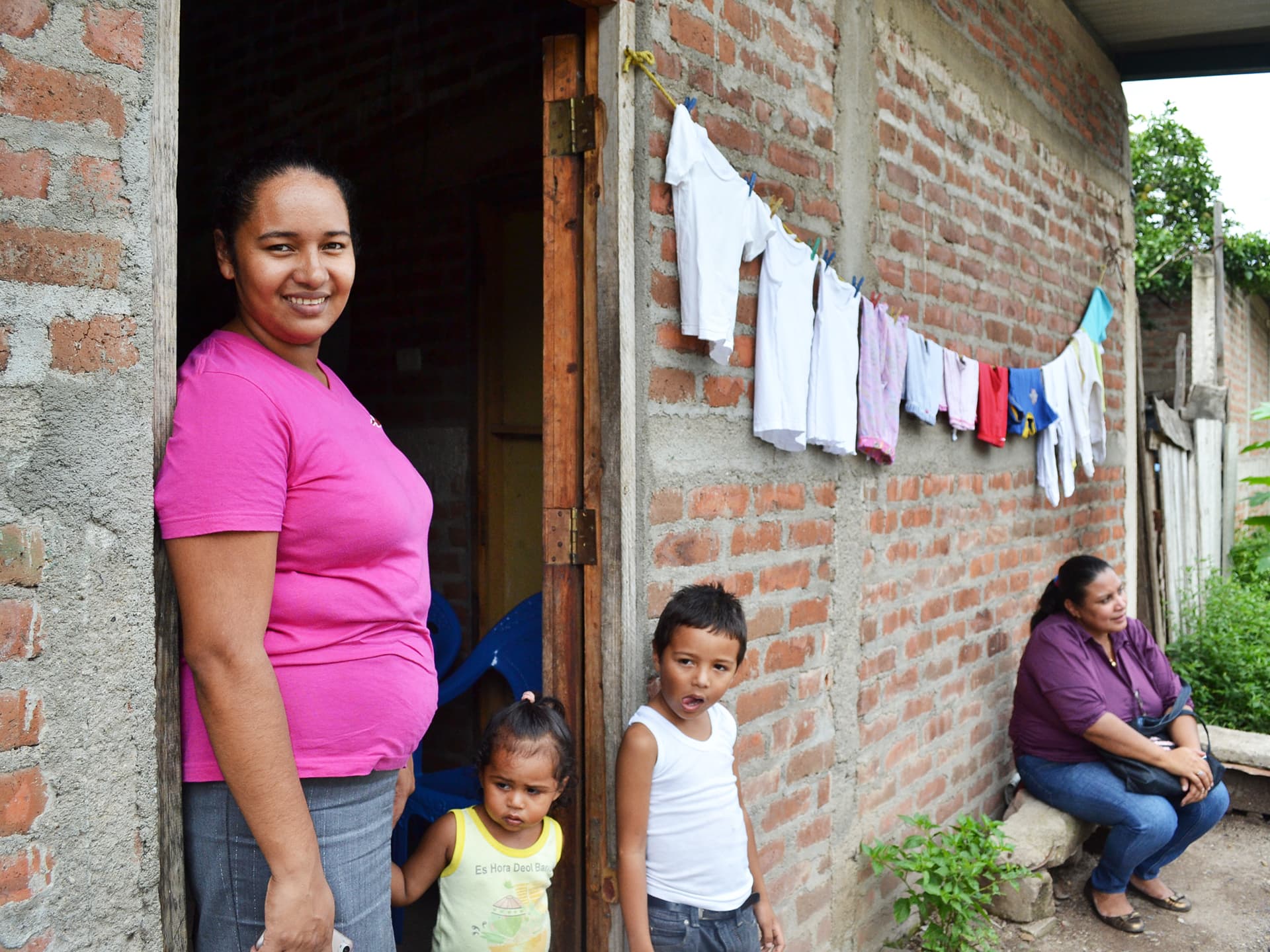Photo: Diakonia A Nicaraguan woman standing outside a house with two kids.