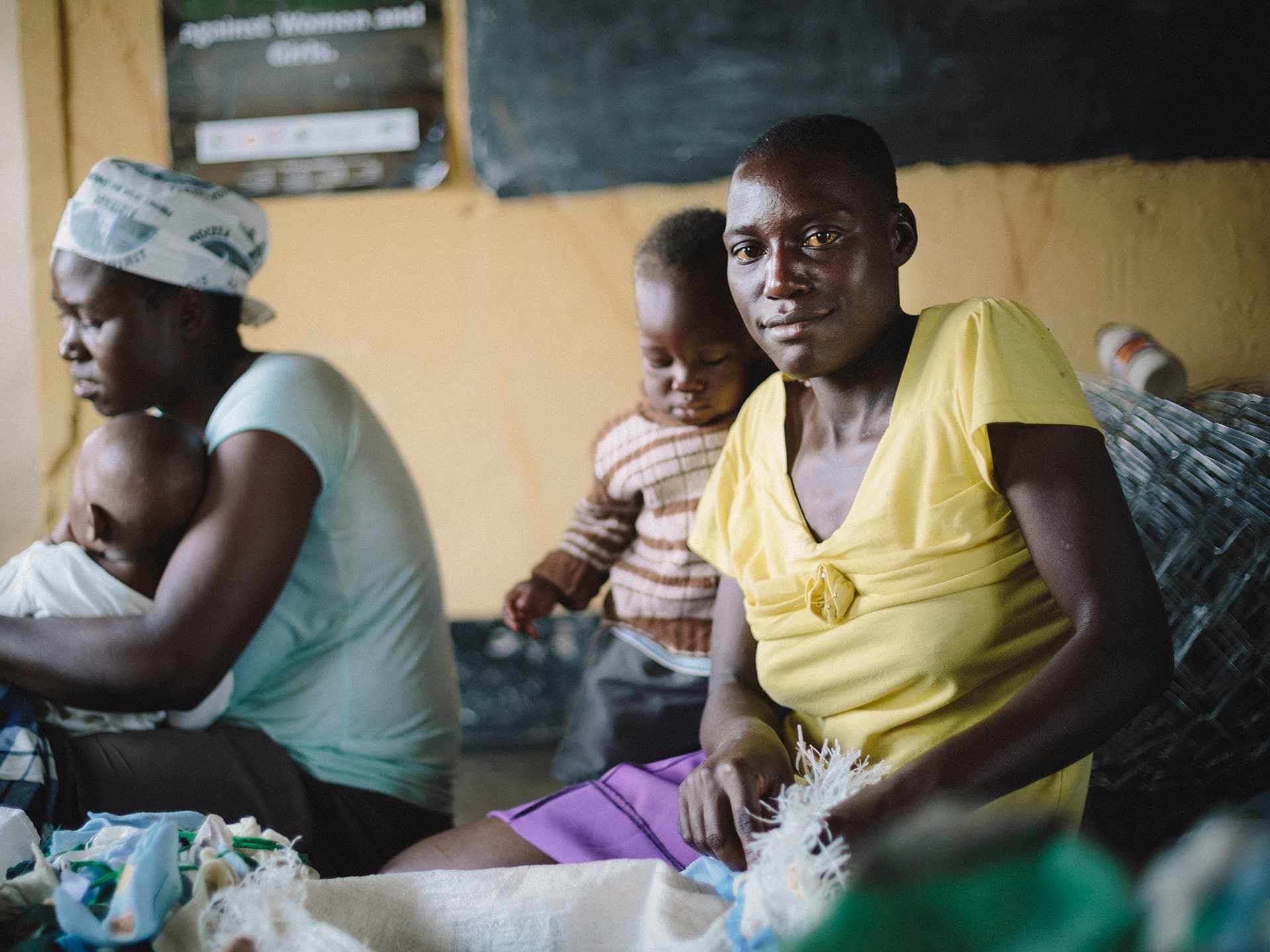 Photo: Anna Hugosson A Zimbabwean woman sitting on a floor sewing with her baby next to her.