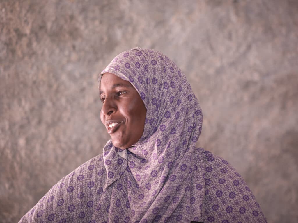 Photo: Diakonia A woman in a purple hijab looking to the side and smiling.