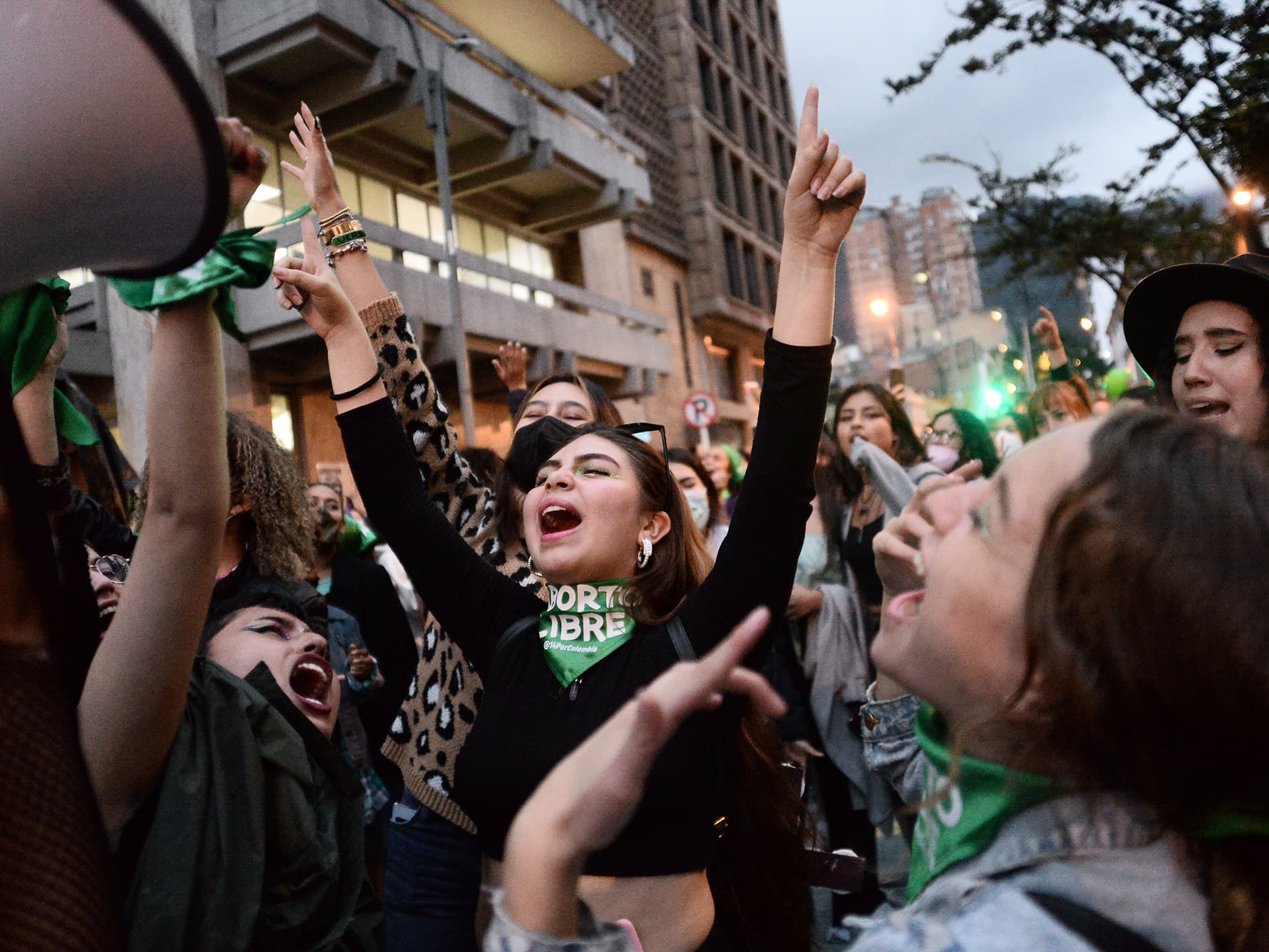 Photo: Lina Gasca A crowd of young women lifting their hands and screaming, wearing green scarves.
