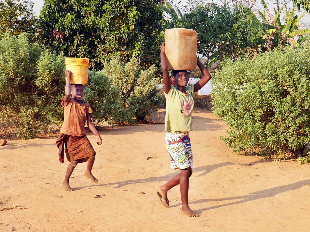 Photo: Diakonia Two Zambian children carrying water containers on their heads.