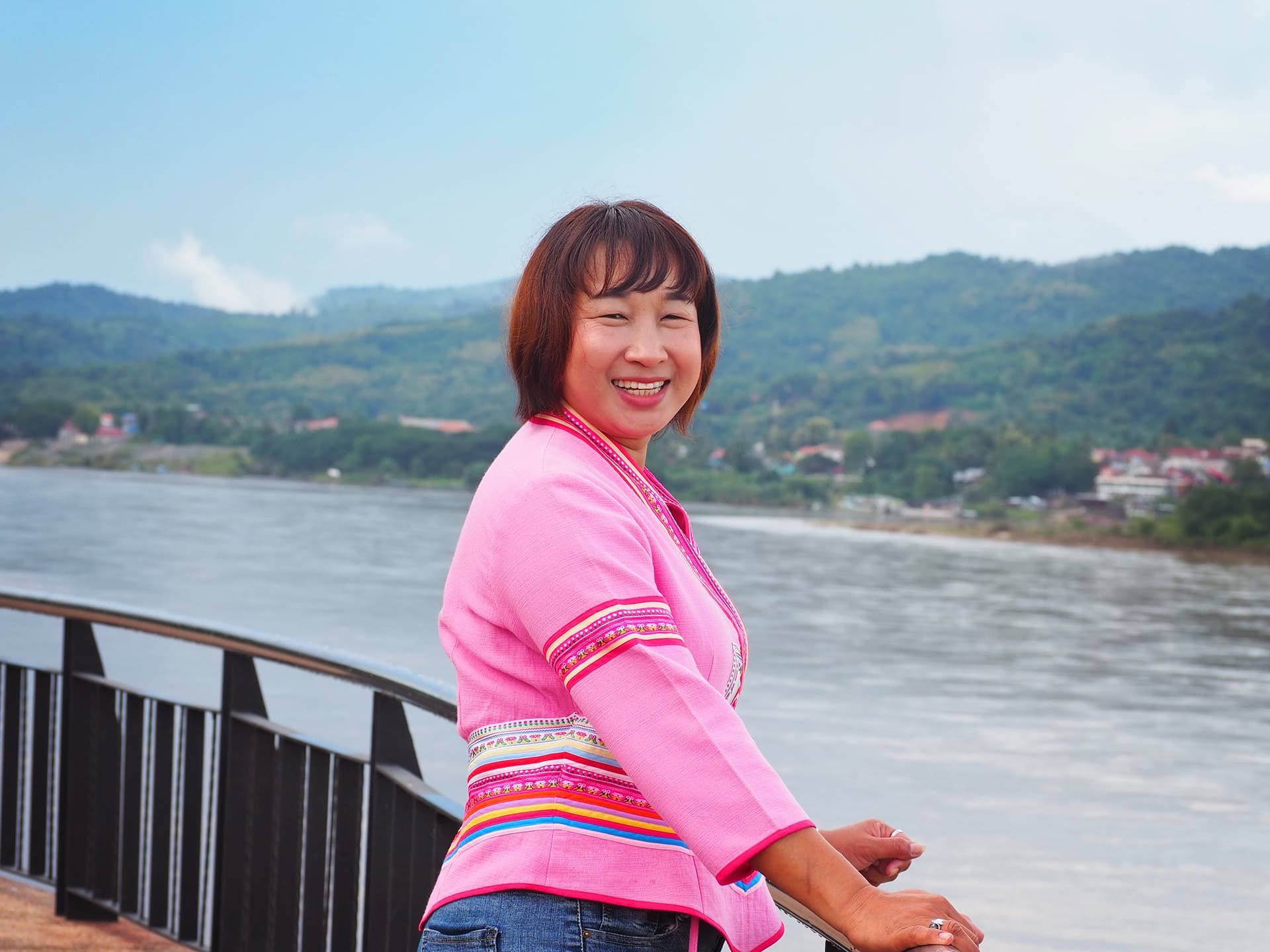 Photo: CFGF A woman in a pink blouse and brown hair looks into the camera, in the background there is a river.