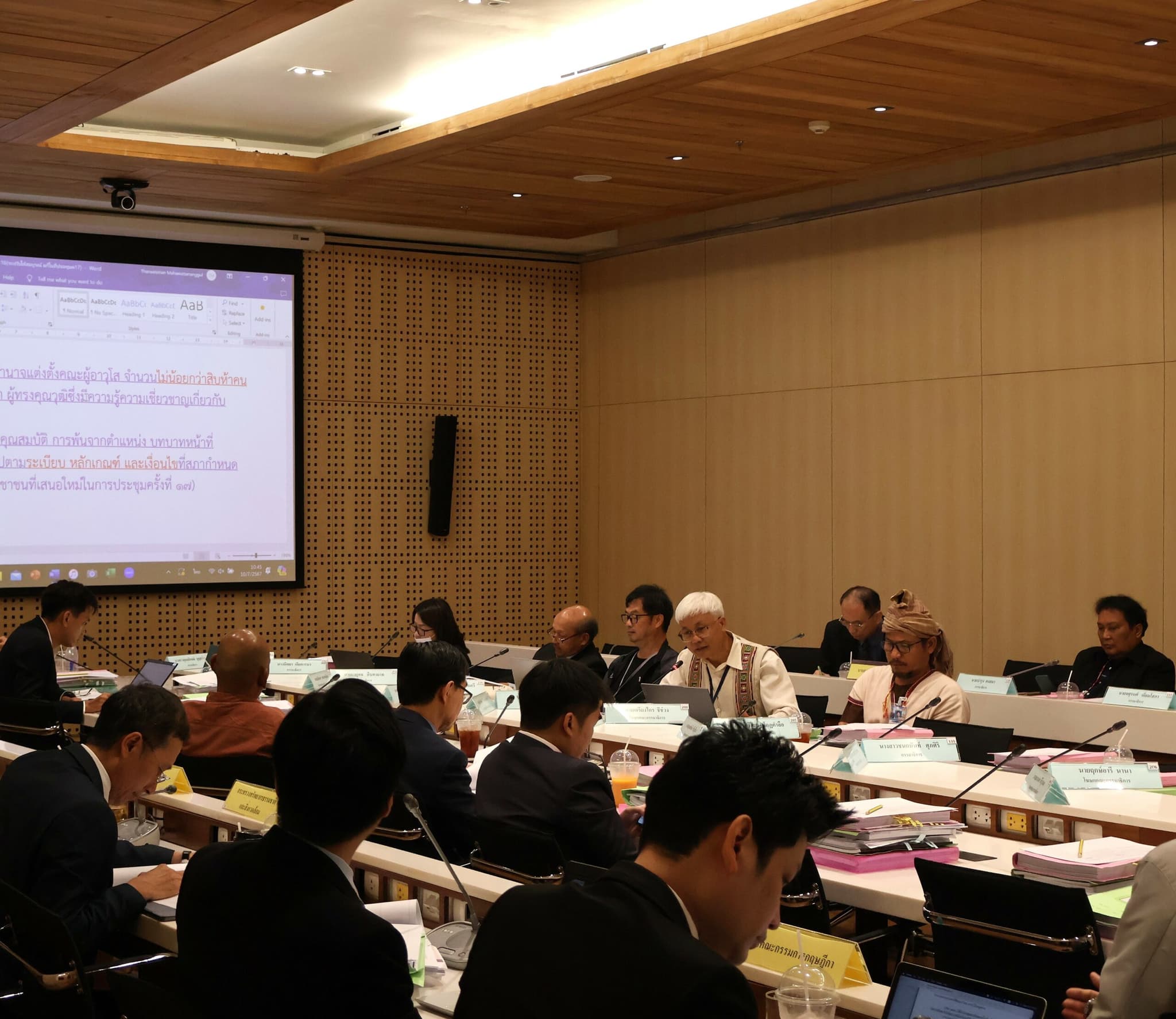 Sakda in a Committee meeting in the Thai parliament to review the draft Indigenous Peoples in Thailand bill. with participants seated around a large table, engaged in discussion with documents and laptops in front of them