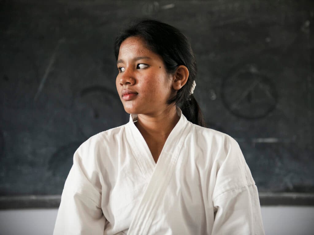 Foto: Gustav Hugosson Flicka i ljus karatedräkt som ser åt vänster. Bakom henne syns en svart skoltavla.