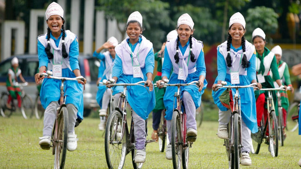 Fyra glada flickor på cykel
