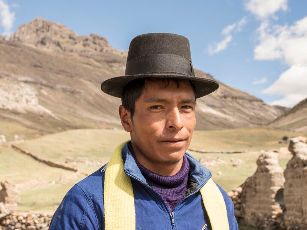 En man med hatt framför ett berg
